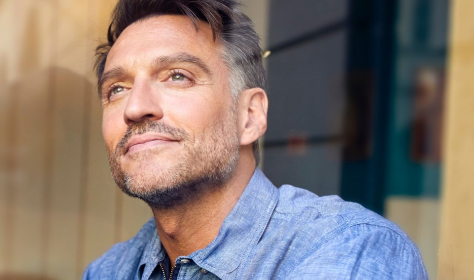 Middle-aged person glances off into the distance with a satisfied look.