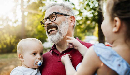 Grandfather holding a baby and a toddler.